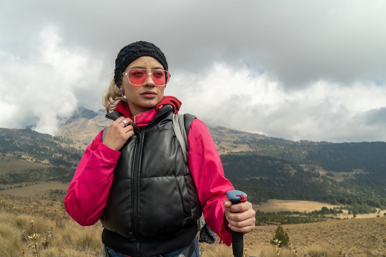 ours-journey Woman in vibrant hiking gear explores a cloudy, mountainous landscape. Adventure awaits.