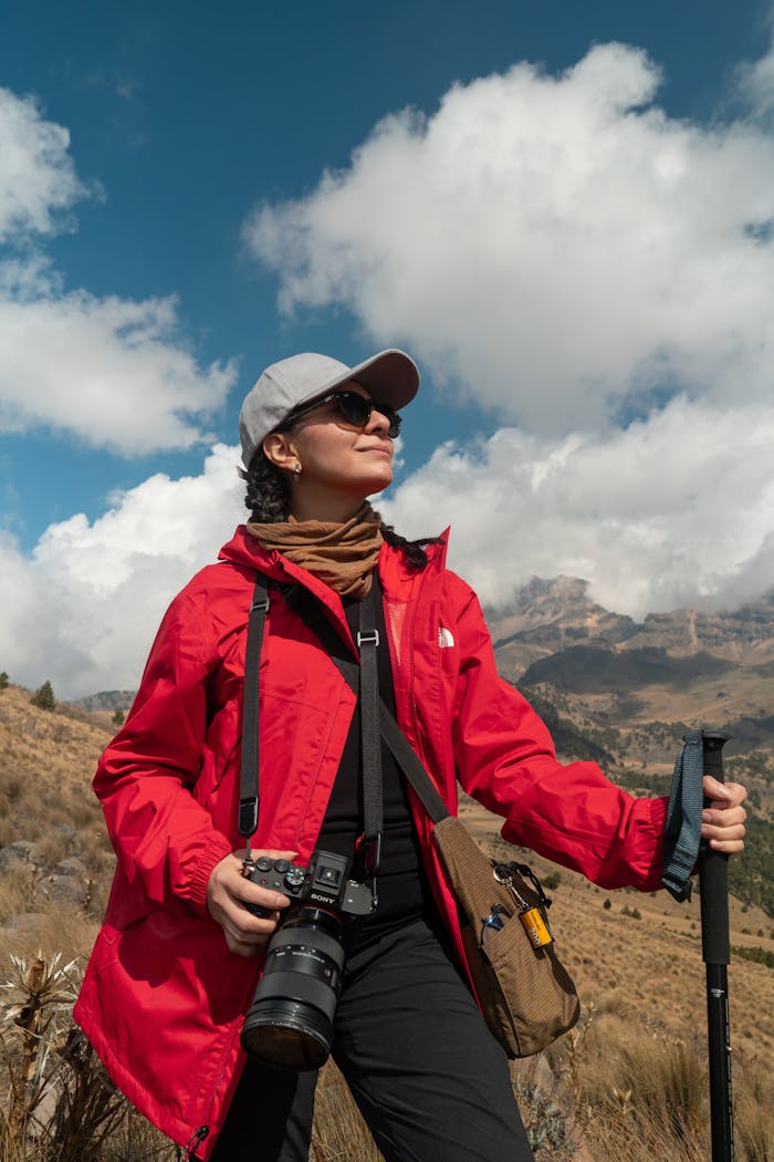 about-01 Woman in red jacket hiking and taking photos in scenic mountain area.