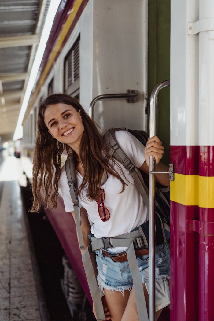 The Art of Drawing Readers In: Your attractive post title goes here Young woman with backpack smiling as she boards a colorful train, ready for an adventure.