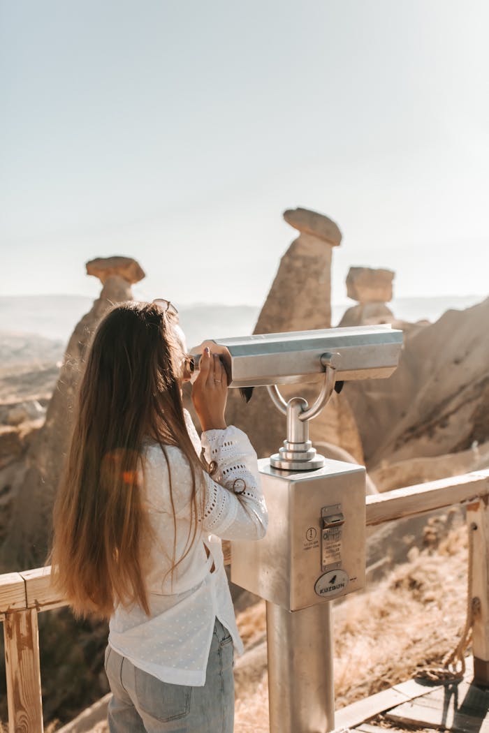 services-01 Woman using a telescope to view the stunning rock formations of Cappadocia, Turkey.